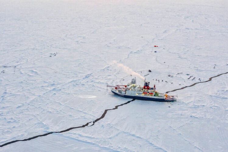 Auf dem Bild ist eine Eislandschaft in Alaska zu sehen und ein Eisbrecherschiff, das im Eis schwimmt.